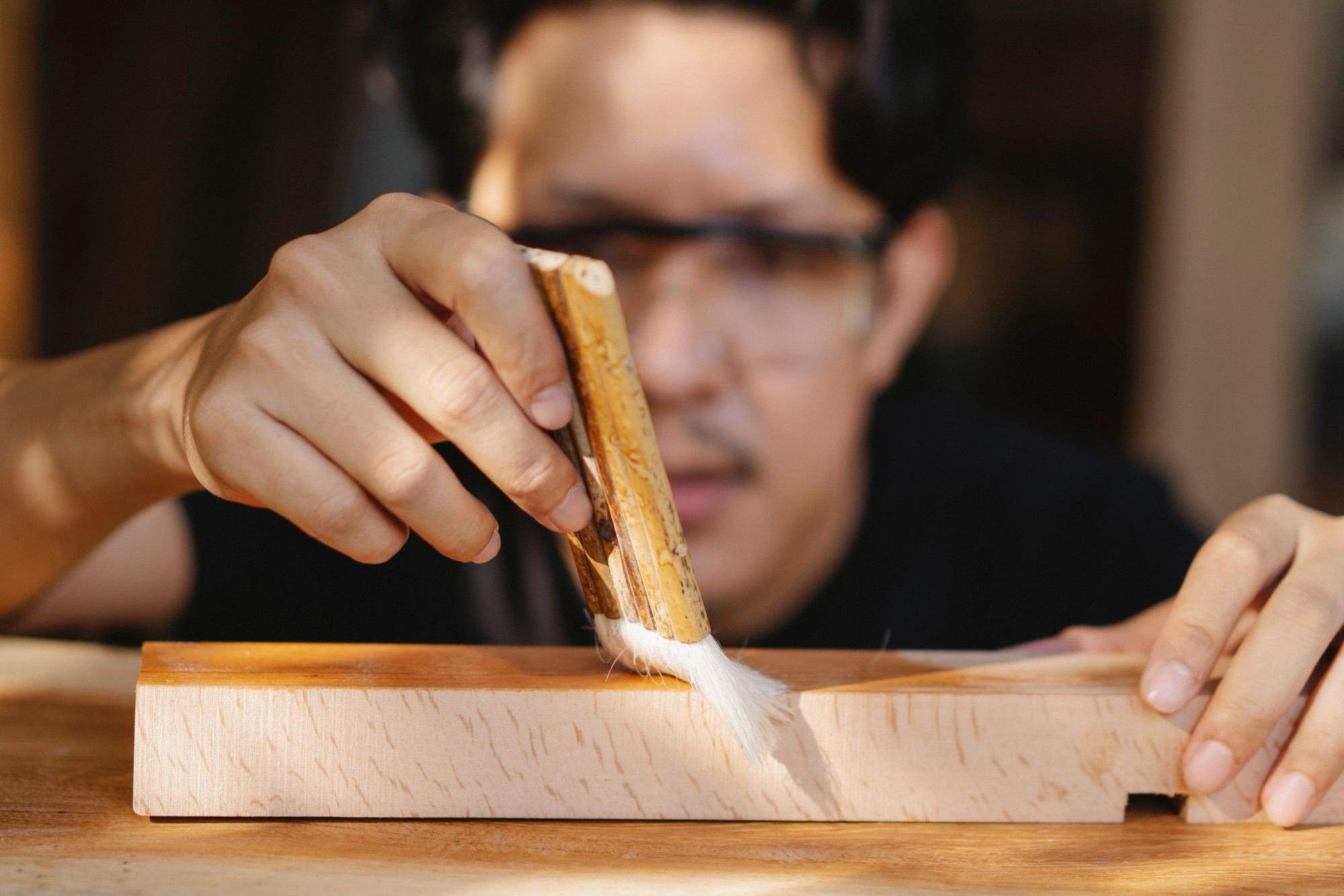 Artigiano che applica una finitura a pennello su un elemento in legno